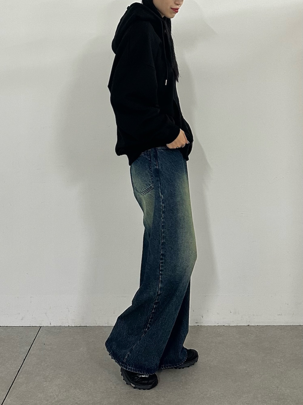 ブラック系のパーカー、ブルー系のデニムパンツ、ブラック系のキャップを着用したレディースの秋コーディネートの2枚目の写真