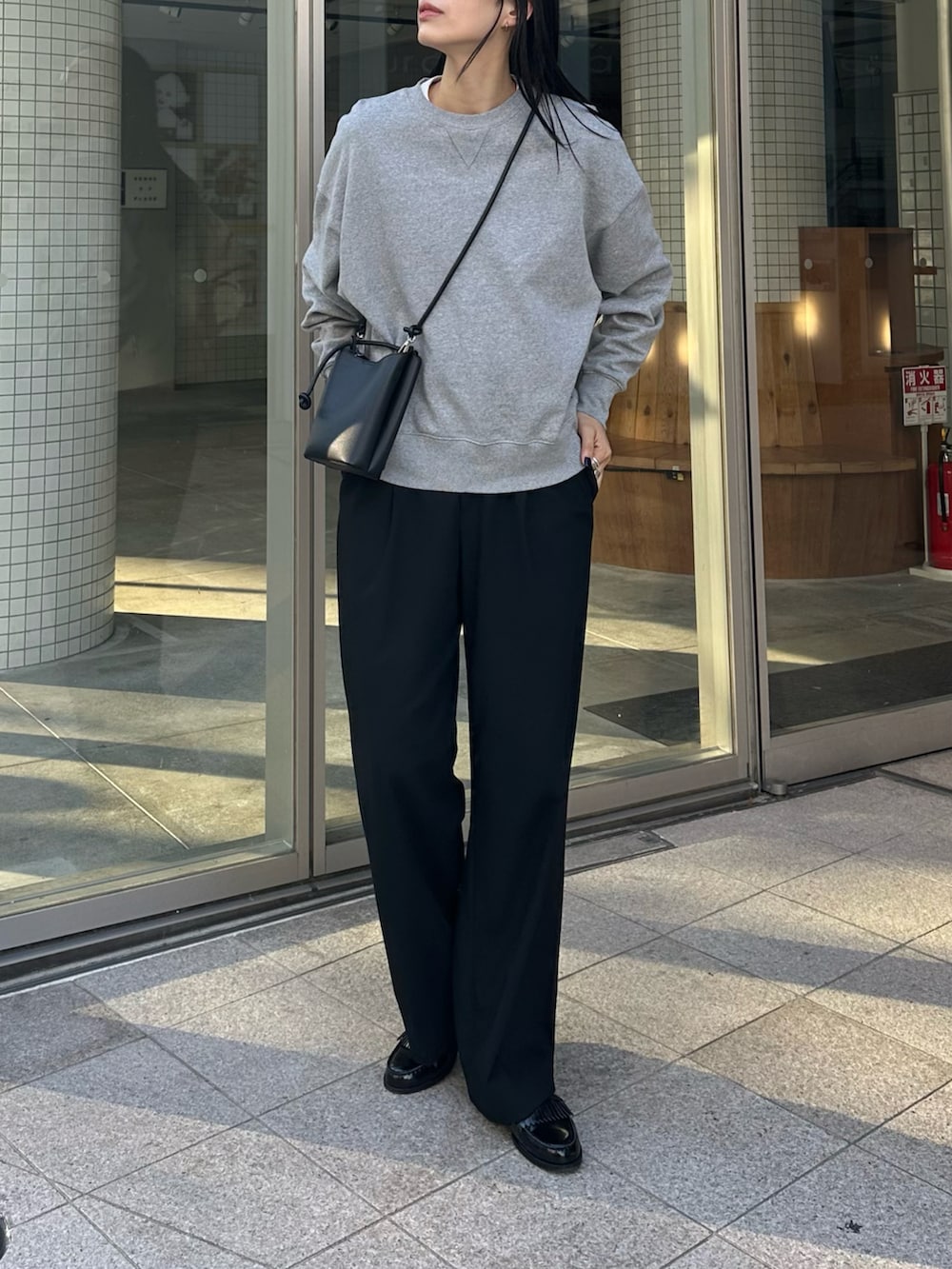 グレー系のスウェット、ブラック系のスラックス、ブラック系のローファーを着用したレディースの冬コーディネートの2枚目の写真