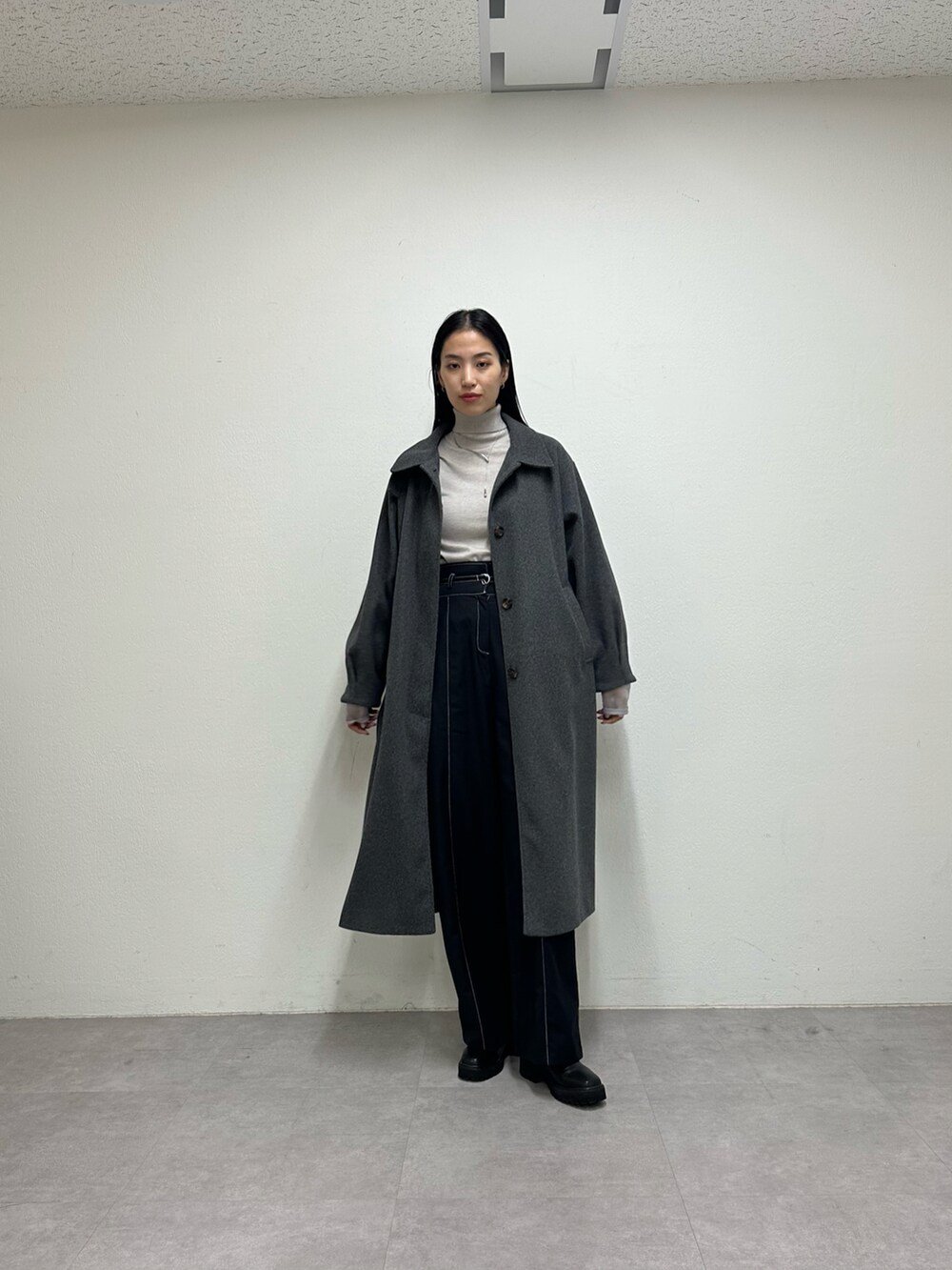 ブラック系のその他パンツ、グレー系のステンカラーコート、グレー系のニット/セーターを着用したレディースの秋コーディネートの3枚目の写真