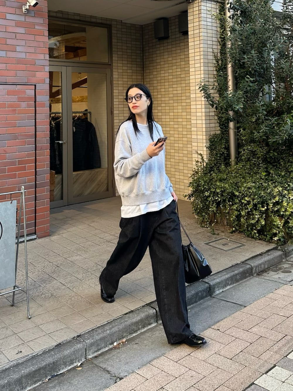 グレー系のスウェット、ブラック系のデニムパンツを着用したレディースの冬コーディネートの3枚目の写真