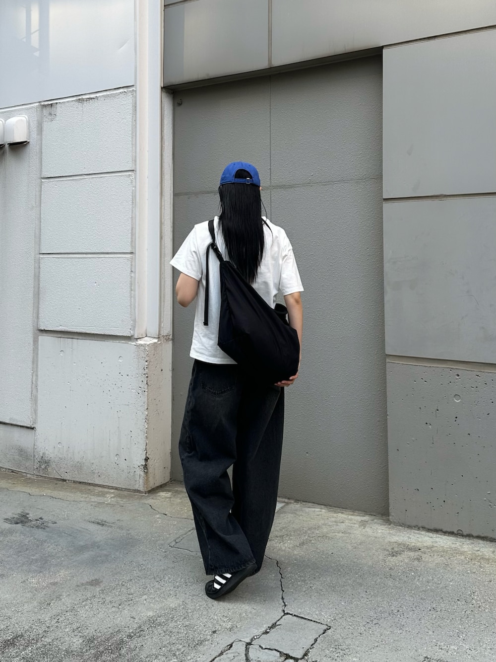 ブラック系のデニムパンツ、ホワイト系のTシャツ/カットソー、ブラック系のショルダーバッグを着用したレディースの春コーディネートの3枚目の写真