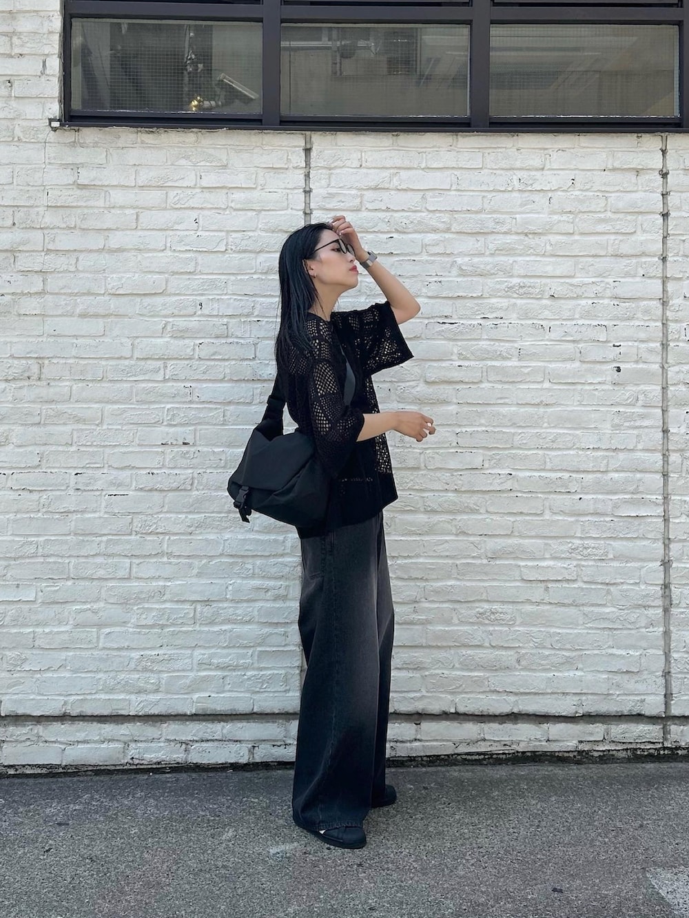 ブラック系のデニムパンツ、ブラック系のメッセンジャーバッグ、ブラック系のニット/セーターを着用したレディースの春コーディネートの2枚目の写真