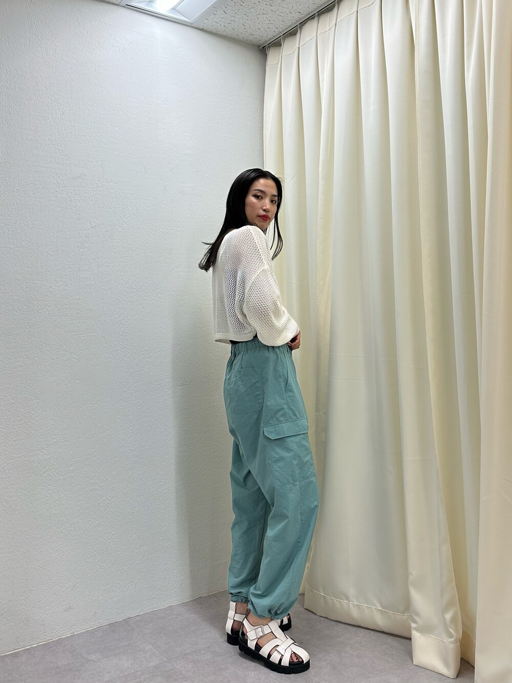 グリーン系のカーゴパンツ、ホワイト系のサンダル、ホワイト系のニット/セーターを着用したレディースの春コーディネートの2枚目の写真