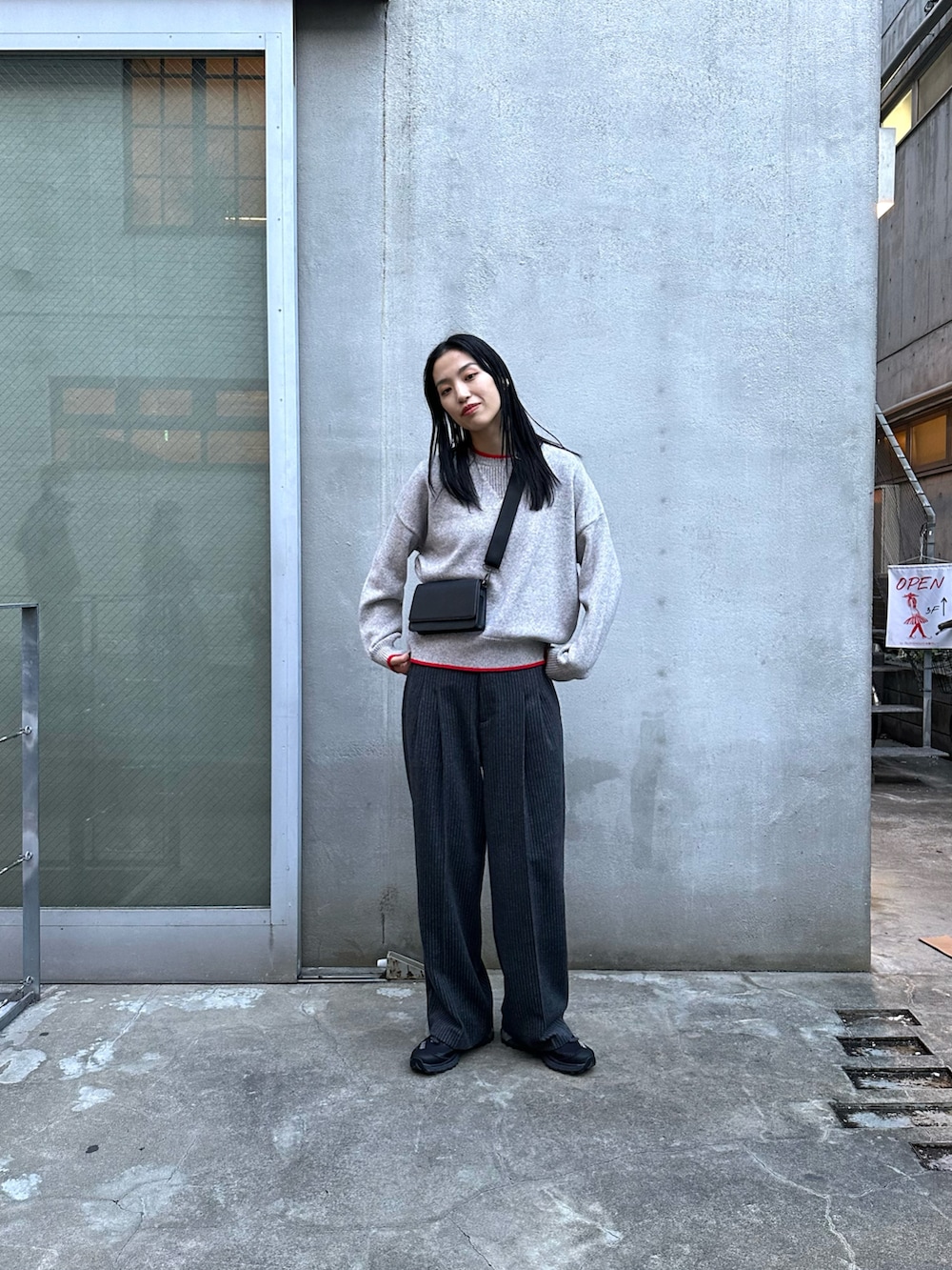 グレー系のスラックス、ブラック系のダウンジャケット/コート、グレー系のニット/セーターを着用したレディースの冬コーディネートの5枚目の写真