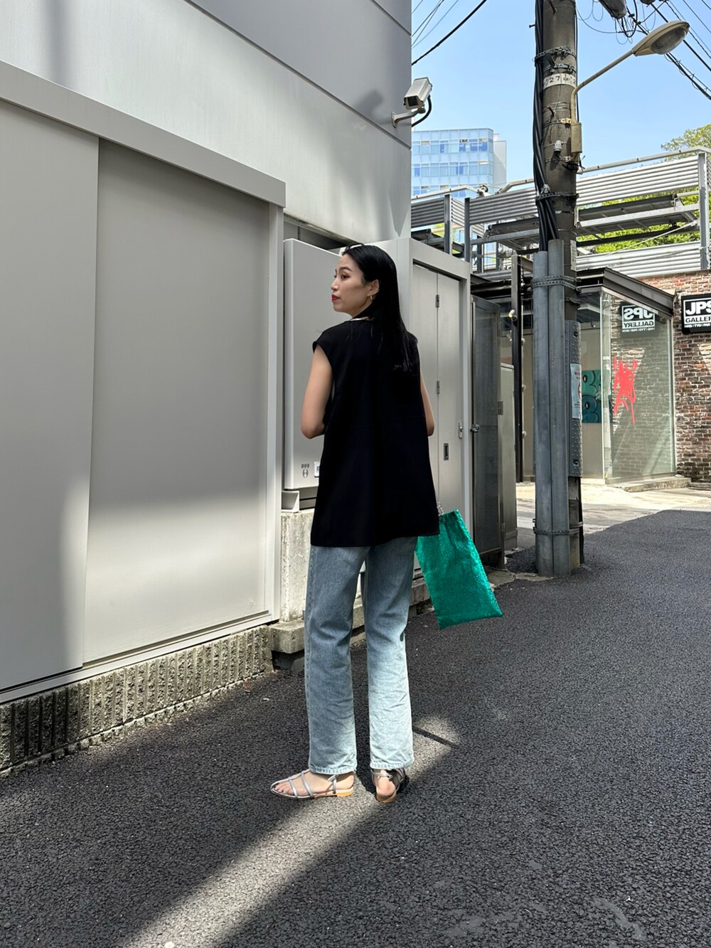 ブルー系のデニムパンツ、シルバー系のサンダル、グリーン系のトートバッグを着用したレディースの春コーディネートの4枚目の写真