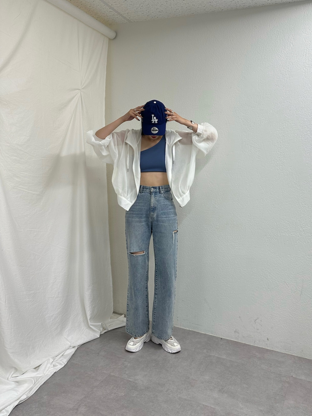 ブルー系のデニムパンツ、ホワイト系のサンダル、ホワイト系のシャツ/ブラウスを着用したレディースの春コーディネートの2枚目の写真