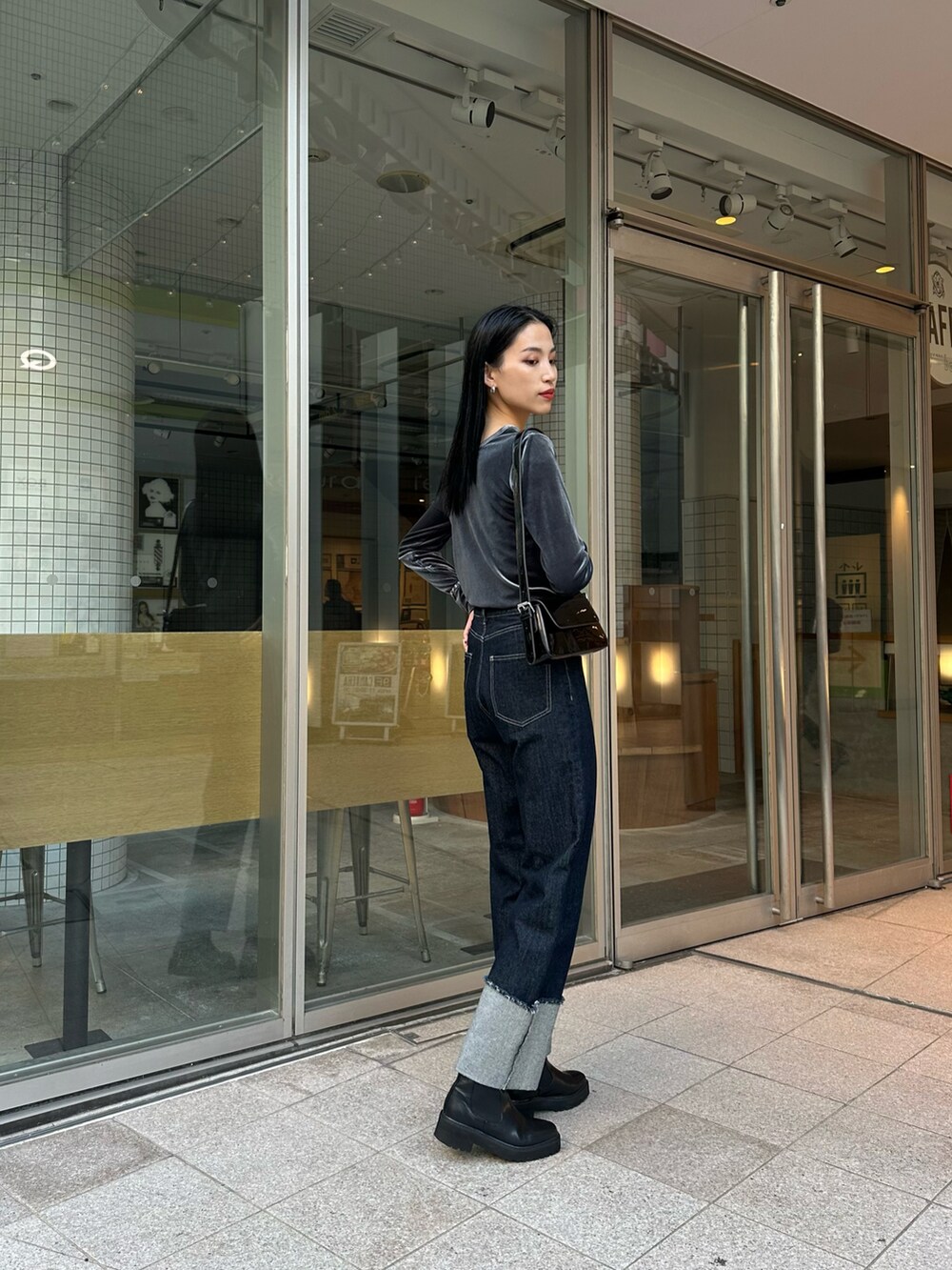 ブルー系のデニムパンツ、グレー系のTシャツ/カットソー、ブラック系のショルダーバッグを着用したレディースの秋コーディネートの2枚目の写真