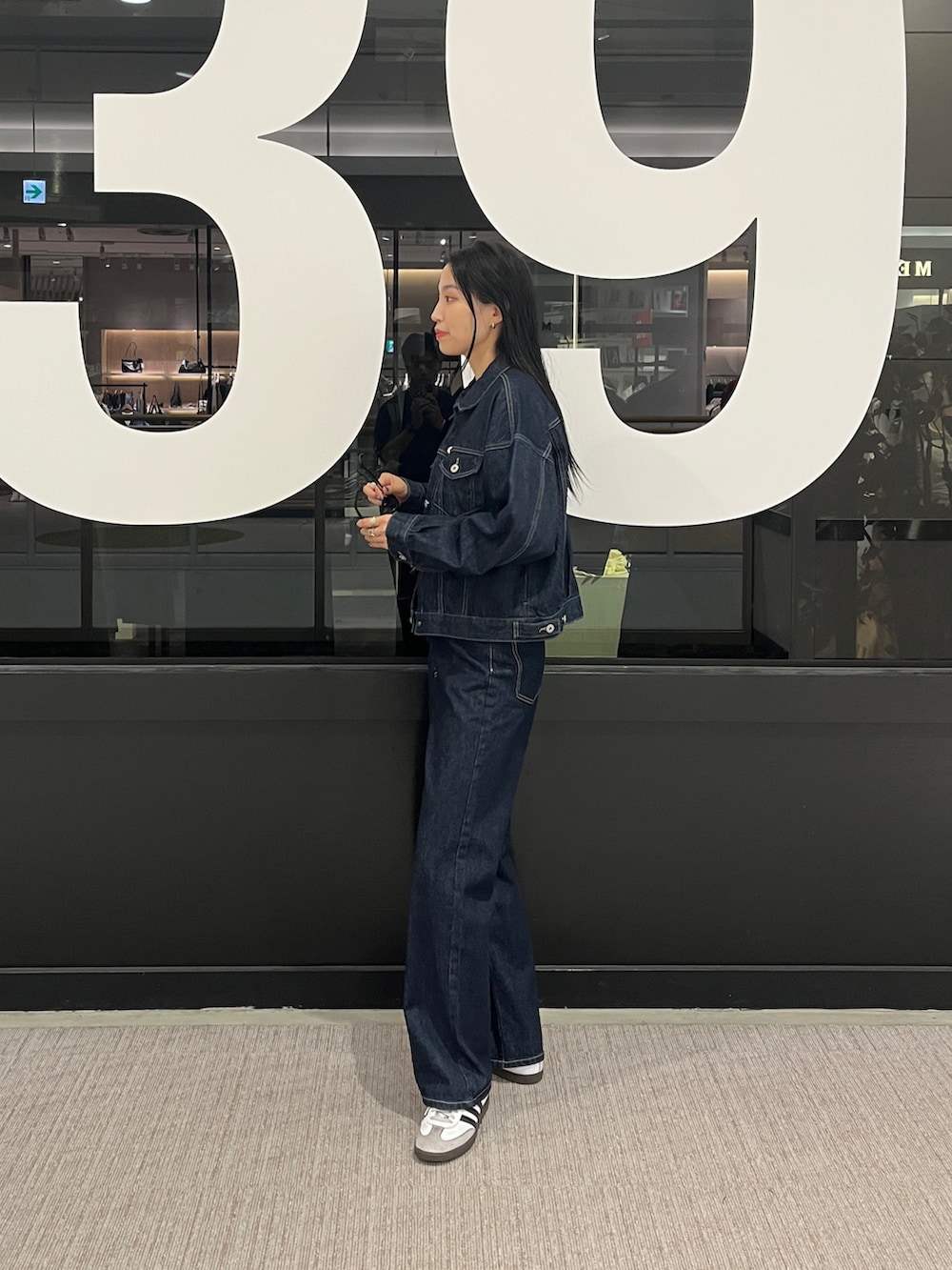 ブルー系のデニムパンツ、ブルー系のデニムジャケット、ホワイト系のタンクトップを着用したレディースの秋コーディネートの2枚目の写真