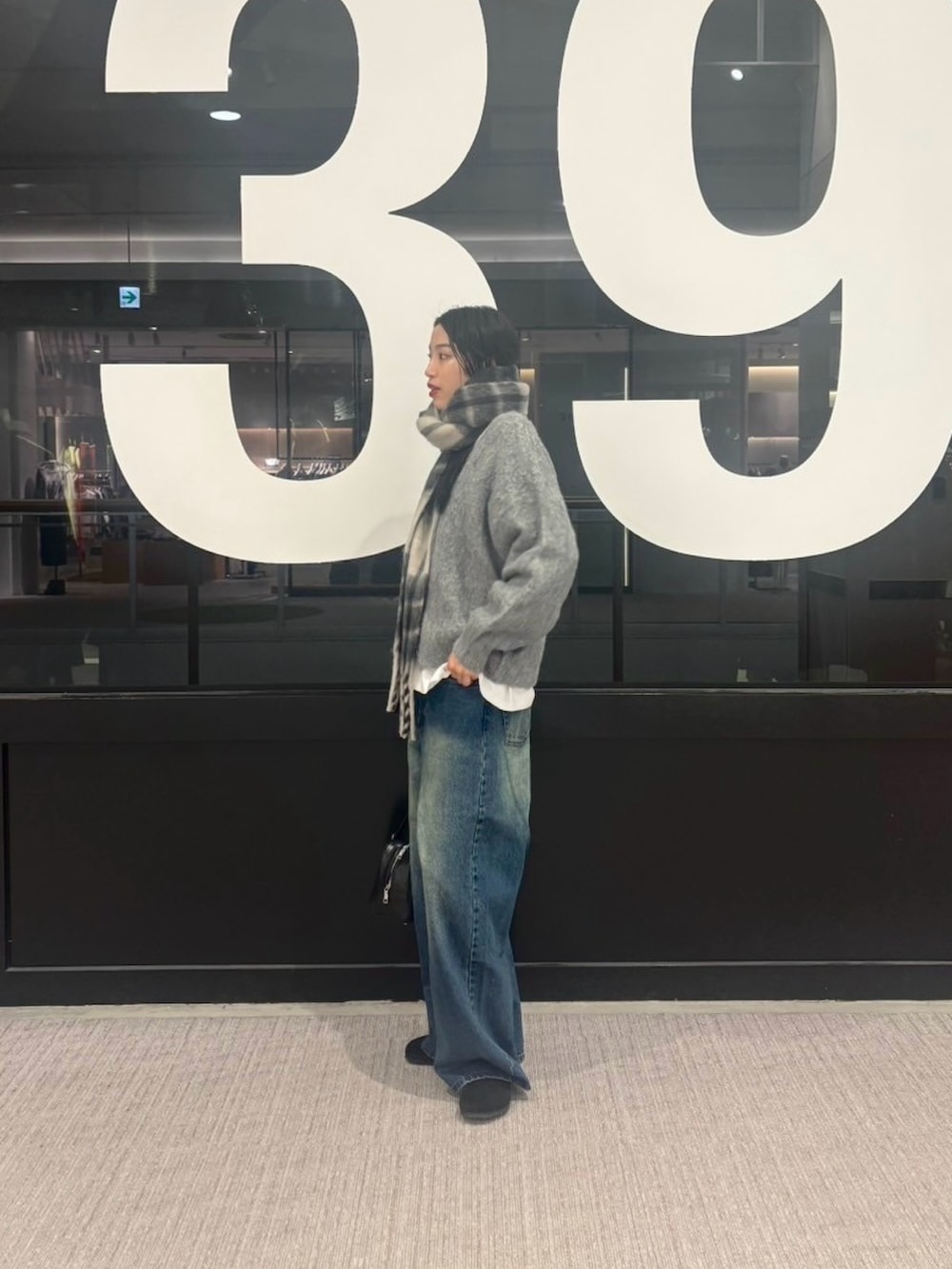 ブルー系のデニムパンツ、グレー系のカーディガン/ボレロ、ホワイト系のTシャツ/カットソーを着用したレディースの冬コーディネートの2枚目の写真