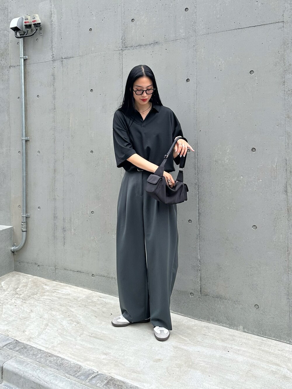 ブラック系のTシャツ/カットソー、ブラック系のショルダーバッグ、グレー系のスラックスを着用したレディースの夏コーディネートの3枚目の写真
