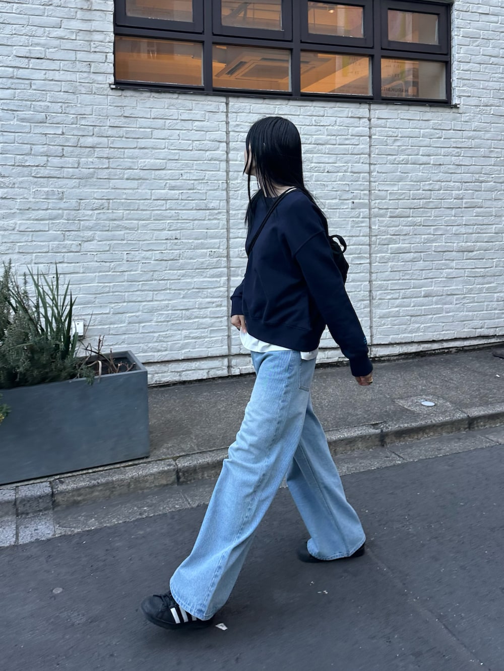 ブルー系のデニムパンツ、ブルー系のスウェット、ブラック系のバックパック/リュックを着用したレディースの冬コーディネートの2枚目の写真