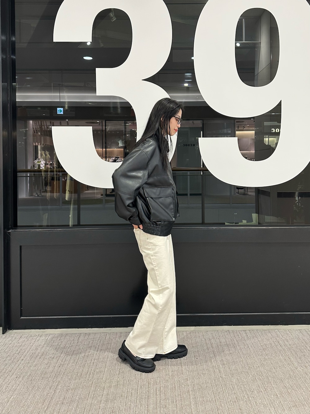 ホワイト系のデニムパンツ、ブラック系のブルゾンを着用したレディースの冬コーディネートの2枚目の写真