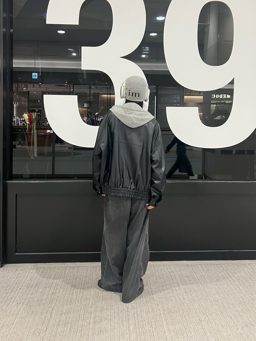 ブラック系のデニムパンツ、ブラック系のブルゾン、グレー系のパーカーを着用したレディースの秋コーディネートの3枚目の写真