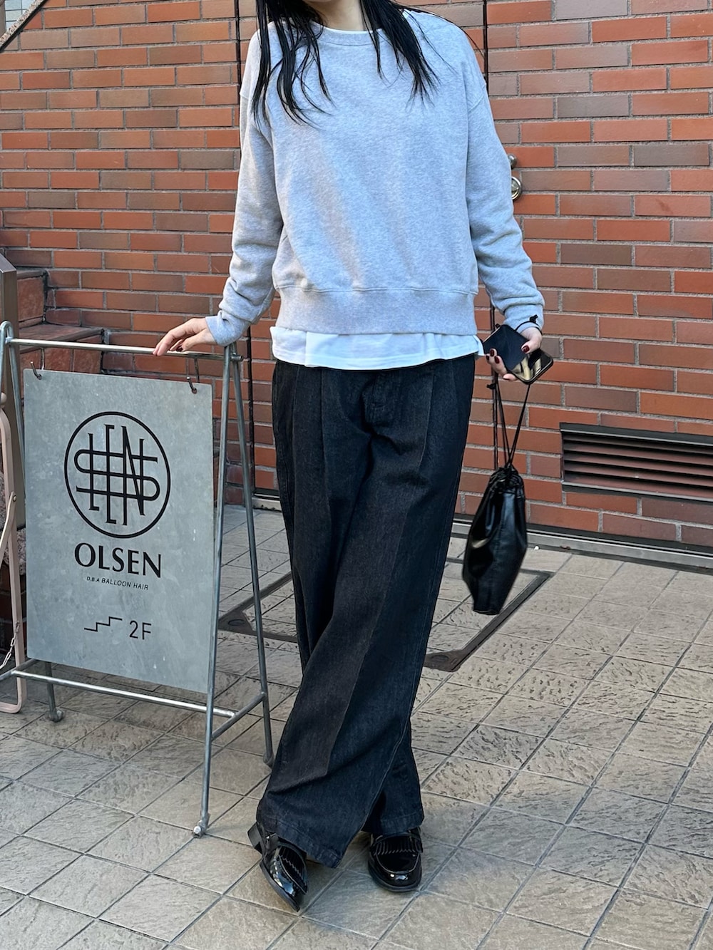 グレー系のスウェット、ブラック系のデニムパンツを着用したレディースの冬コーディネートの4枚目の写真