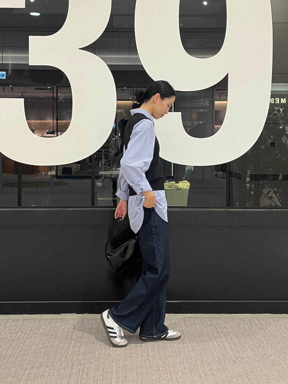 ブルー系のデニムパンツ、ブルー系のシャツ/ブラウス、ブラック系のベストを着用したレディースの秋コーディネートの3枚目の写真