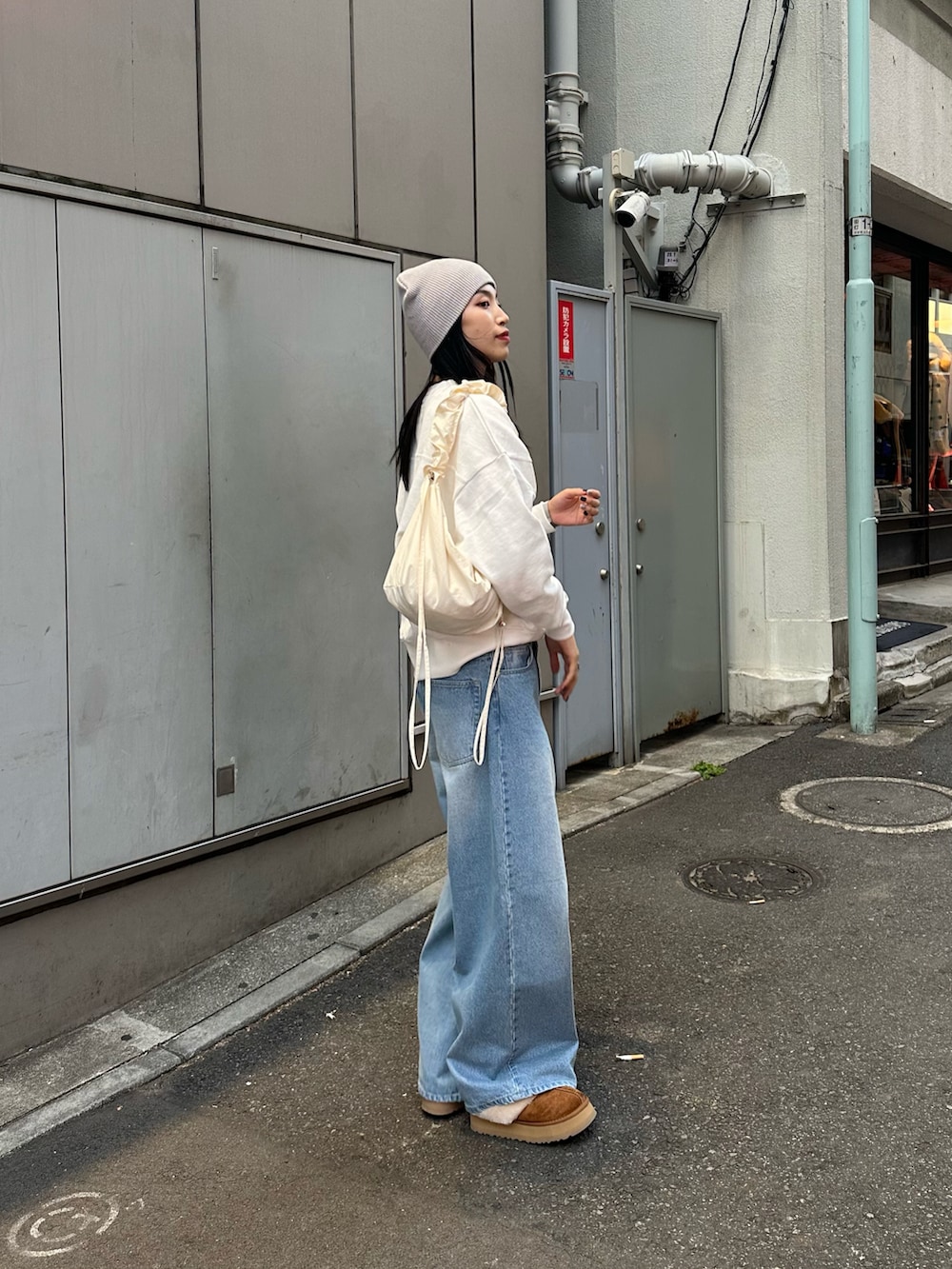 ホワイト系のショルダーバッグ、ブルー系のデニムパンツ、ホワイト系のスウェットを着用したレディースの冬コーディネートの3枚目の写真