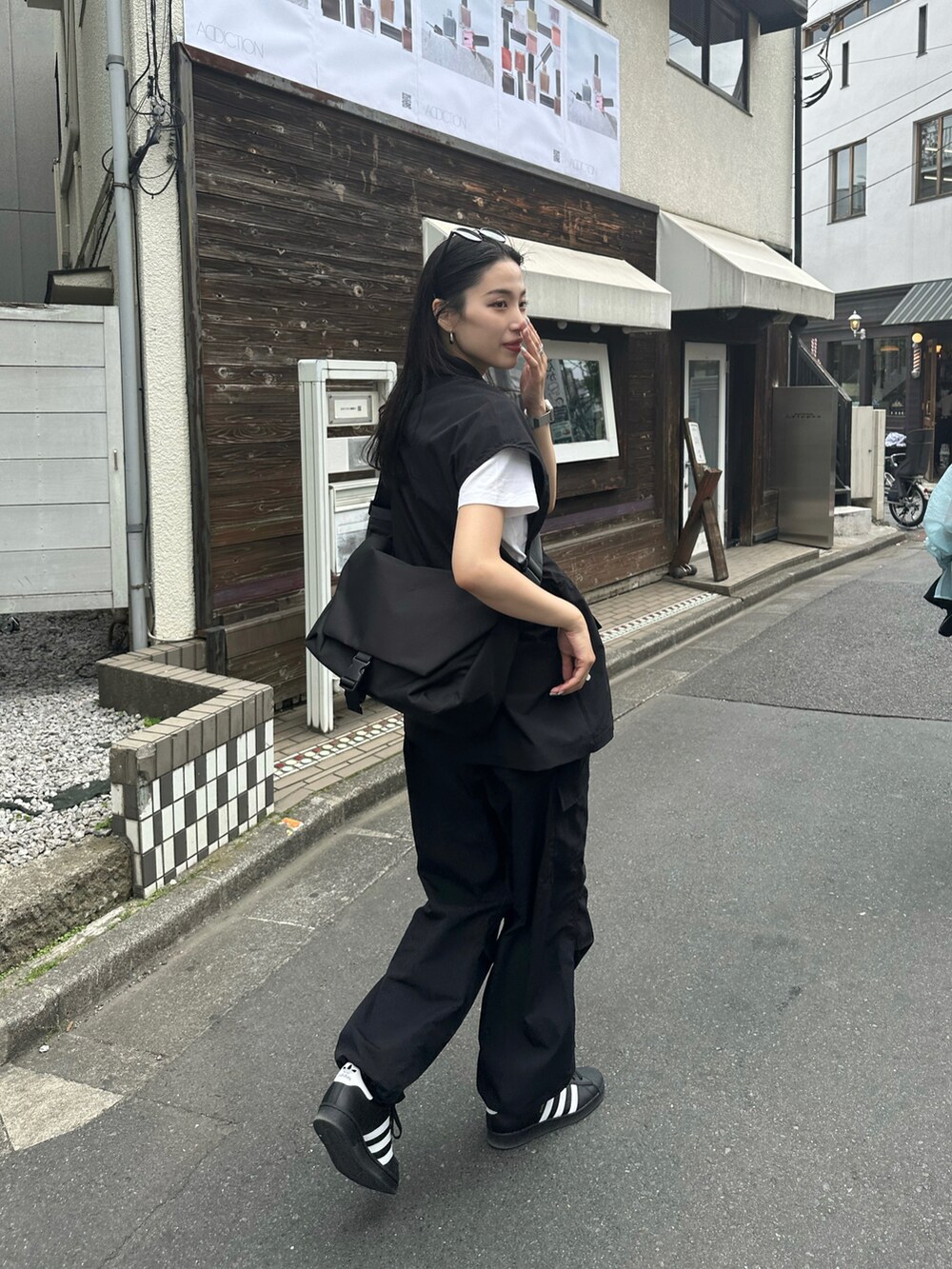 ブラック系のベストを着用したレディースの春コーディネートの2枚目の写真