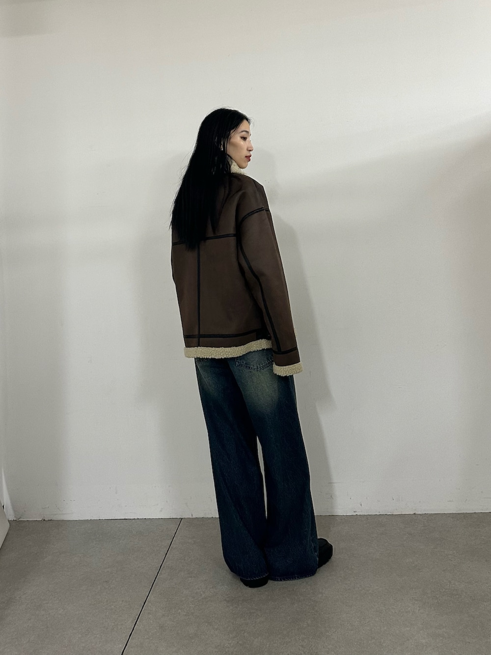 ブルー系のデニムパンツ、ブラウン系のムートンコート、ホワイト系のTシャツ/カットソーを着用したレディースの秋コーディネートの3枚目の写真