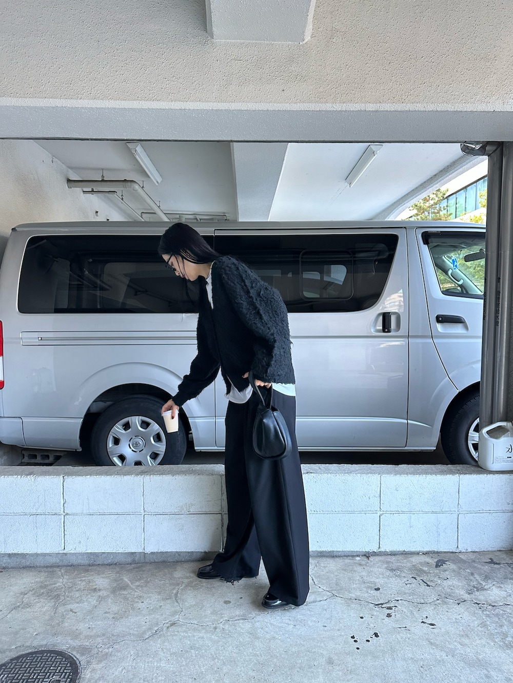 ブラック系のカーディガン/ボレロ、ホワイト系のTシャツ/カットソー、ブラック系のハンドバッグを着用したレディースの冬コーディネートの2枚目の写真