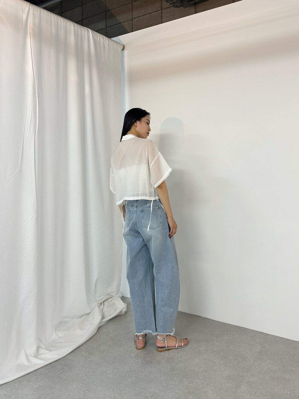 ブルー系のデニムパンツ、シルバー系のサンダル、ホワイト系のキャミソールを着用したレディースの夏コーディネートの2枚目の写真