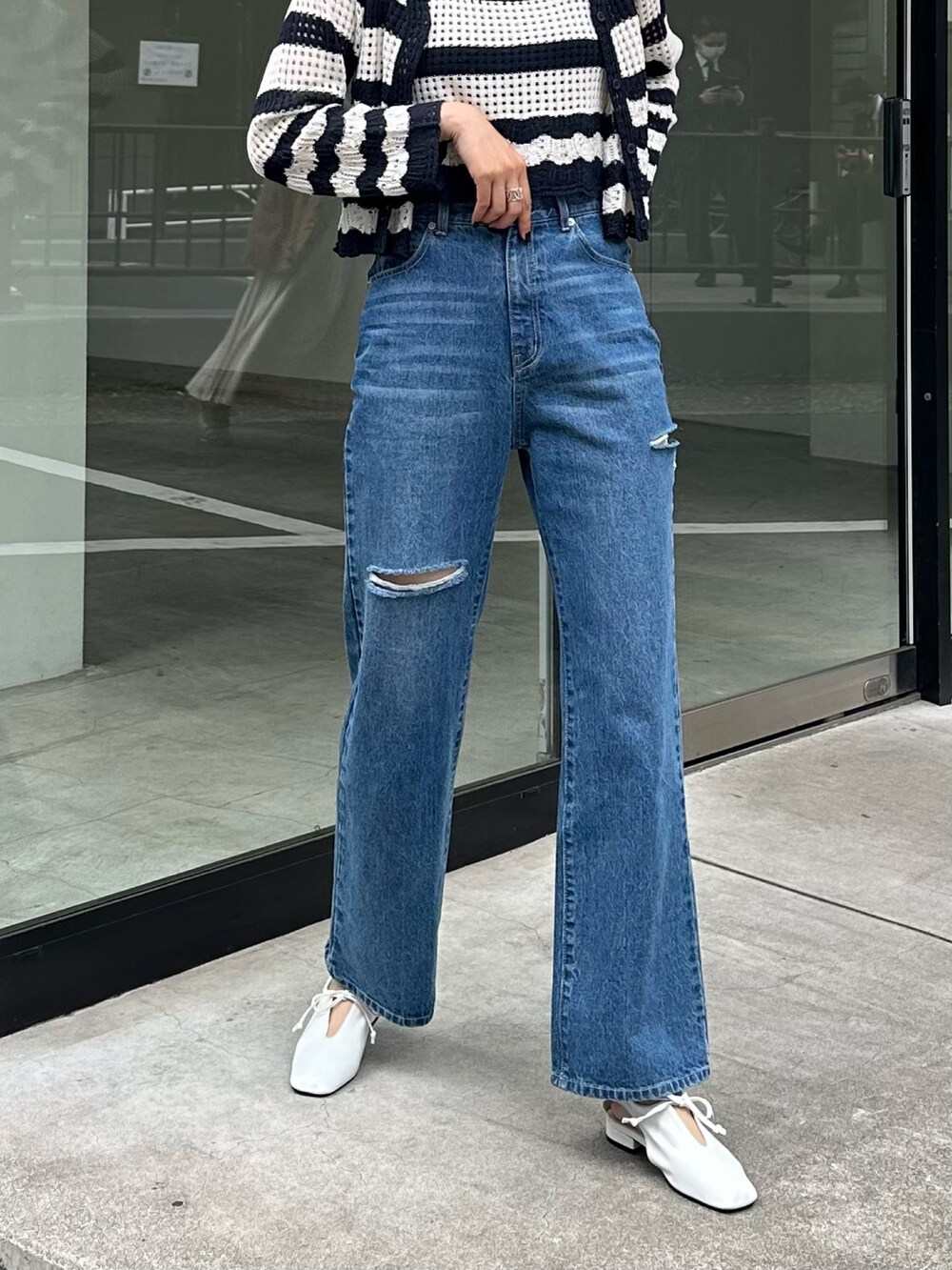 ブルー系のデニムパンツ、ホワイト系のパンプス、ホワイト系のアンサンブルを着用したレディースの春コーディネートの3枚目の写真