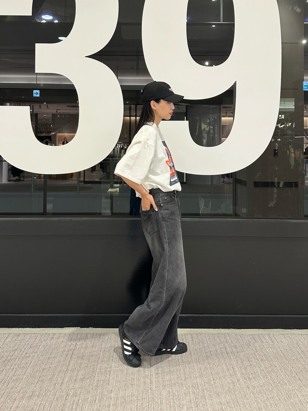 ブラック系のデニムパンツ、ホワイト系のTシャツ/カットソー、ブラック系のキャップを着用したレディースの春コーディネートの2枚目の写真