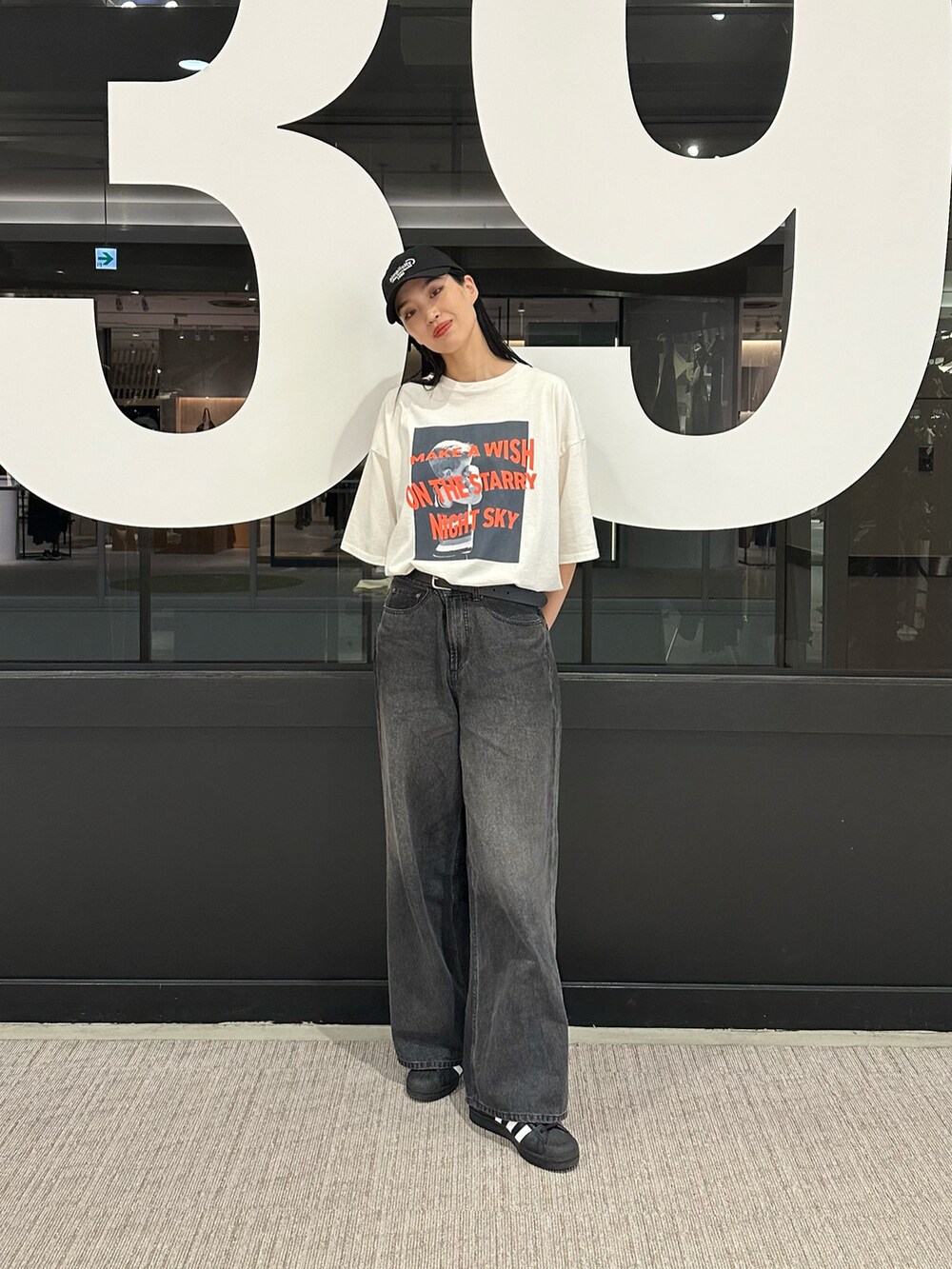 ブラック系のデニムパンツ、ホワイト系のTシャツ/カットソー、ブラック系のキャップを着用したレディースの春コーディネートの4枚目の写真