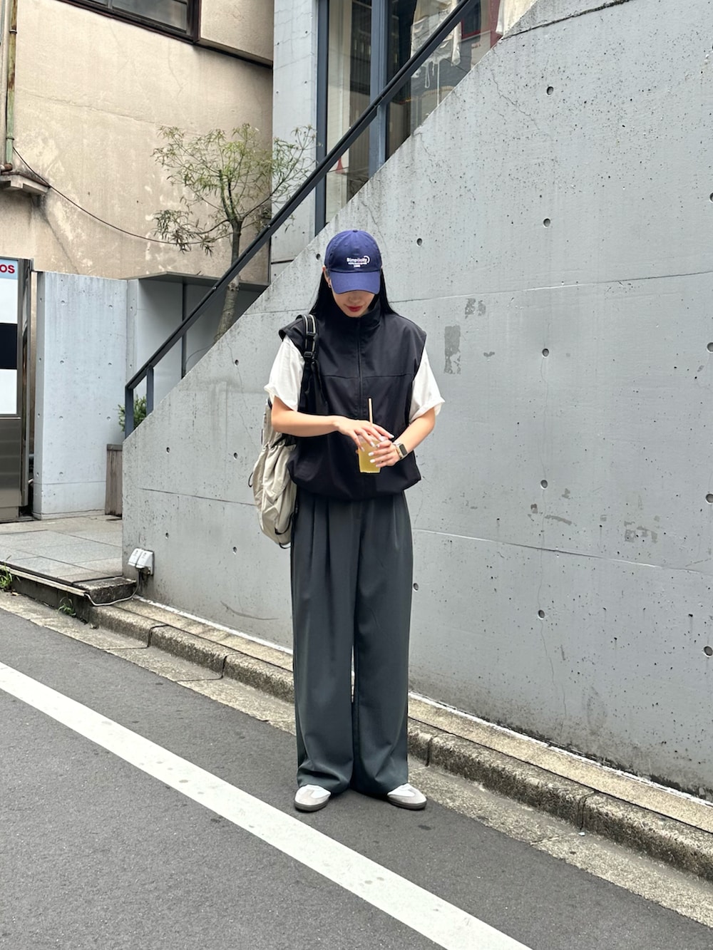 グレー系のスラックス、ブラック系のベスト、ホワイト系のTシャツ/カットソーを着用したレディースの夏コーディネートの3枚目の写真