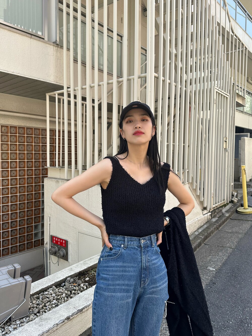 ブルー系のデニムパンツ、ブラック系のアンサンブル、ブラック系のサンダルを着用したレディースの春コーディネートの2枚目の写真