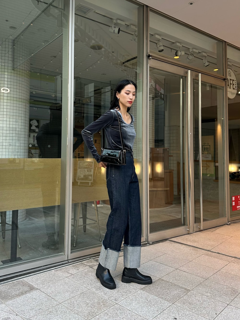 ブルー系のデニムパンツ、グレー系のTシャツ/カットソー、ブラック系のショルダーバッグを着用したレディースの秋コーディネートの3枚目の写真