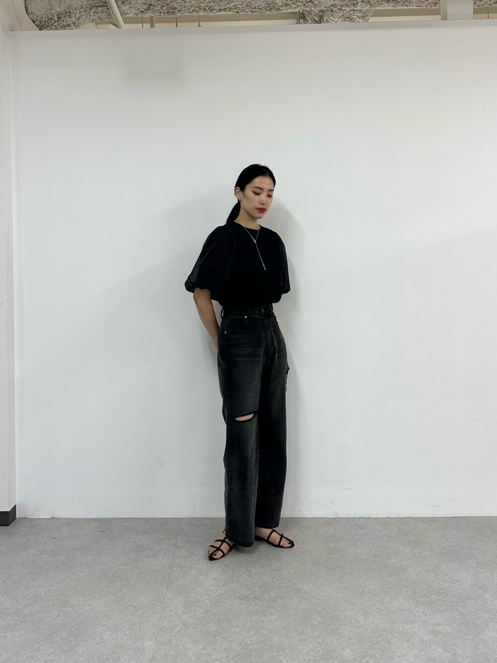 ブラック系のデニムパンツ、ブラック系のサンダル、ブラック系のTシャツ/カットソーを着用したレディースの夏コーディネートの2枚目の写真