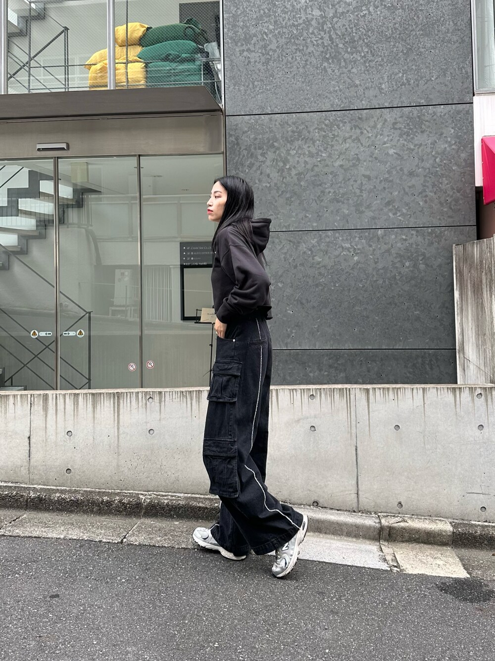 ブラック系のパーカー、ブラック系のデニムパンツ、ホワイト系のショルダーバッグを着用したレディースの秋コーディネートの2枚目の写真