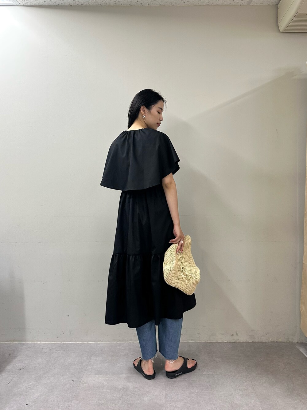 ブラック系のワンピース、ブラック系のサンダル、ブルー系のデニムパンツを着用したレディースの春コーディネートの3枚目の写真