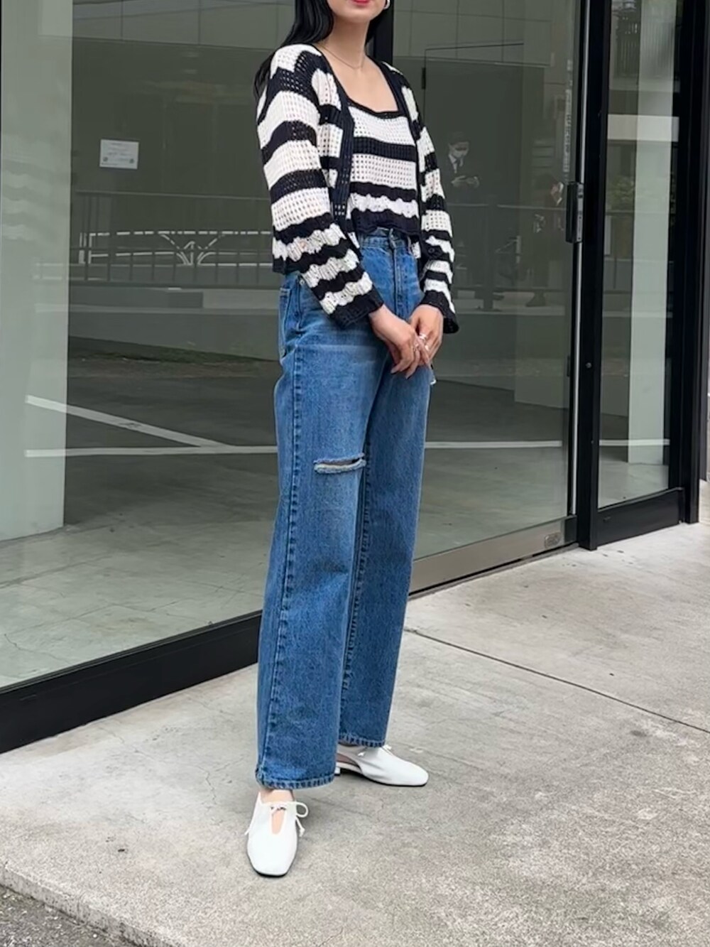 ブルー系のデニムパンツ、ホワイト系のパンプス、ホワイト系のアンサンブルを着用したレディースの春コーディネートの2枚目の写真