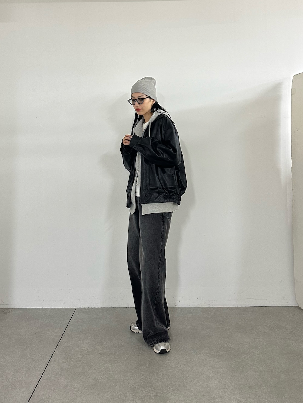 グレー系のパーカー、ブラック系のブルゾン、ブラック系のデニムパンツを着用したレディースの秋コーディネートの4枚目の写真