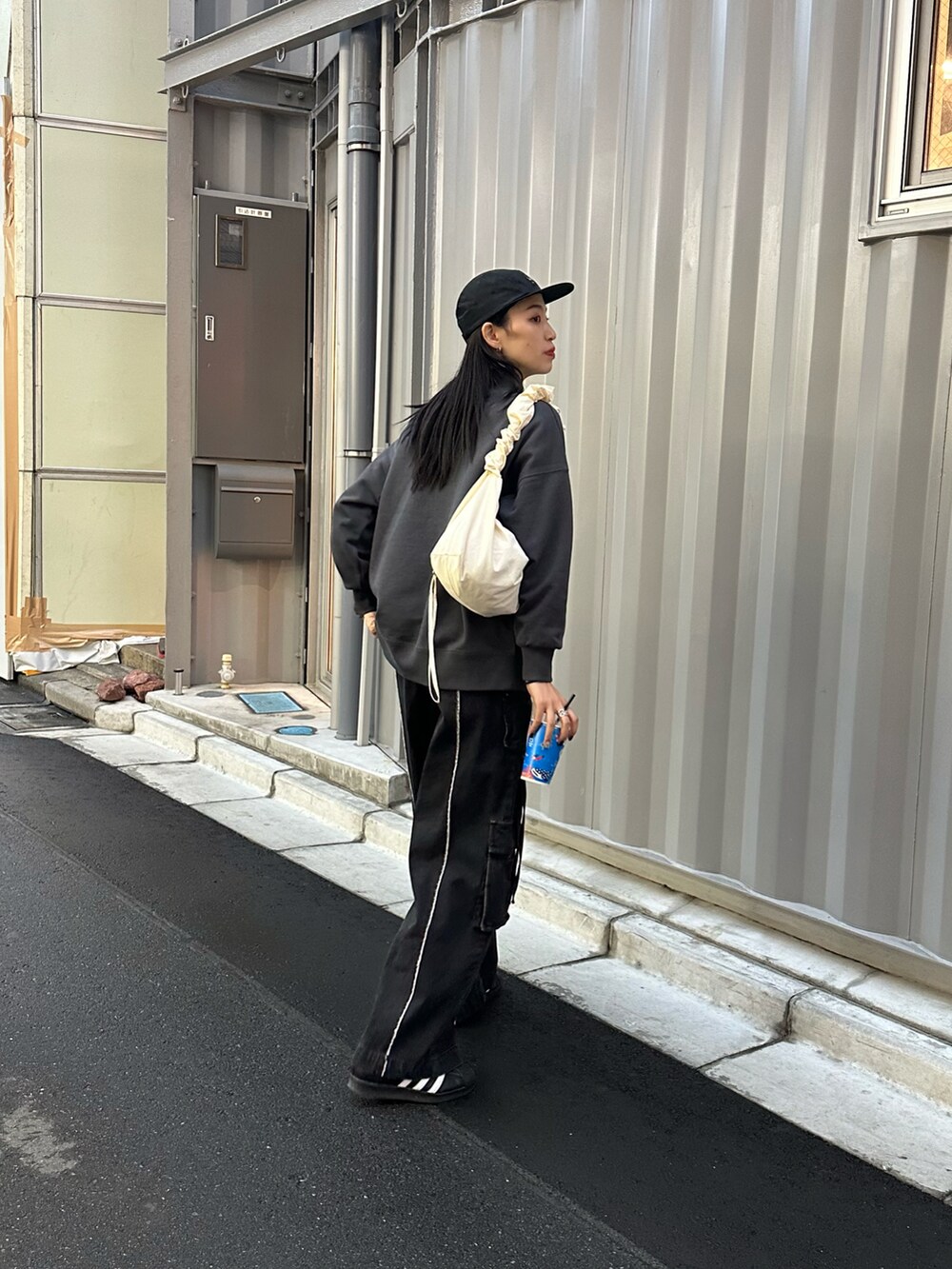 ブラック系のスウェット、ブラック系のデニムパンツ、ホワイト系のショルダーバッグを着用したレディースの冬コーディネートの3枚目の写真