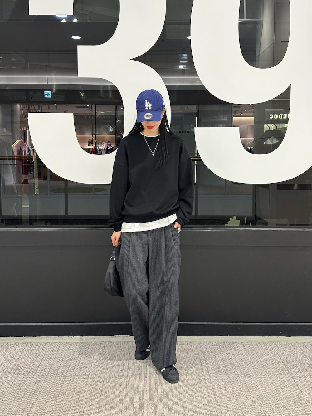 ブラック系のスウェット、ホワイト系のTシャツ/カットソー、グレー系のスラックスを着用したレディースの秋コーディネートの4枚目の写真