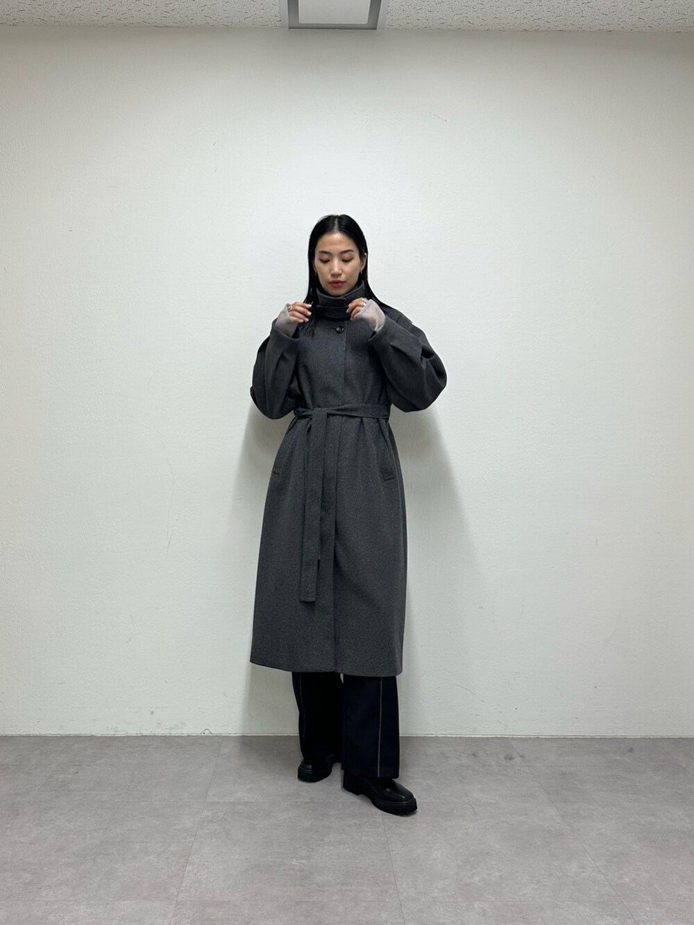 ブラック系のその他パンツ、グレー系のステンカラーコート、グレー系のニット/セーターを着用したレディースの秋コーディネートの2枚目の写真