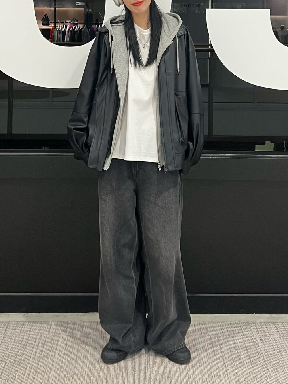 ブラック系のデニムパンツ、ブラック系のブルゾン、グレー系のパーカーを着用したレディースの秋コーディネートの4枚目の写真