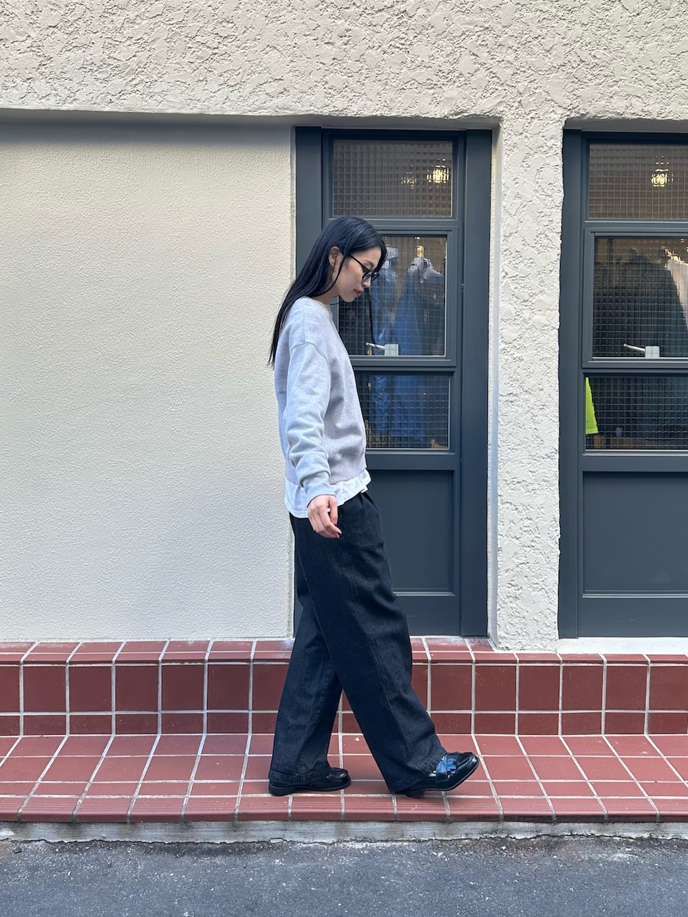 グレー系のスウェット、ブラック系のデニムパンツを着用したレディースの冬コーディネートの2枚目の写真