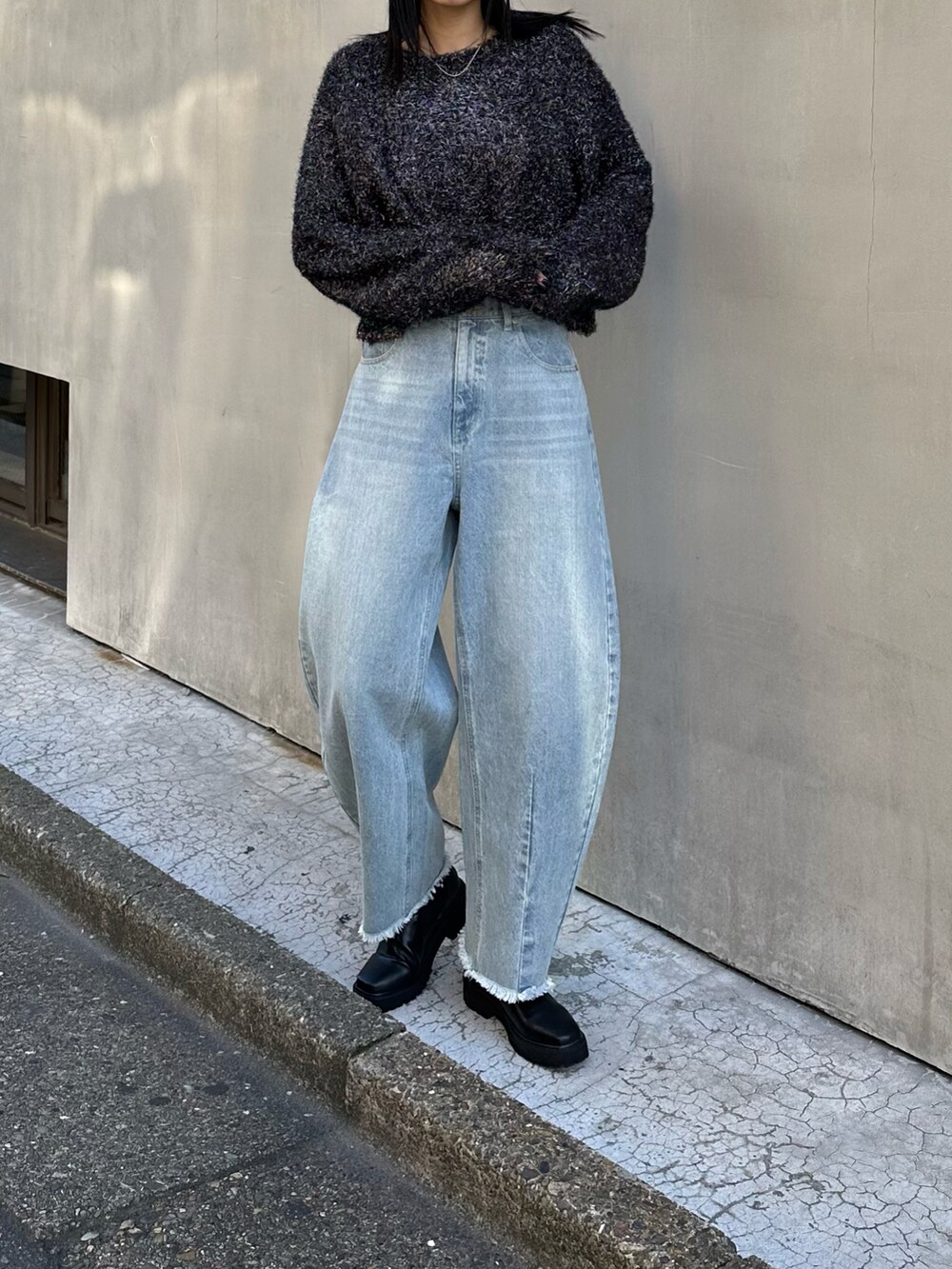 ブラック系のニット/セーター、ブルー系のデニムパンツ、ブラック系のブーツを着用したレディースの秋コーディネートの2枚目の写真