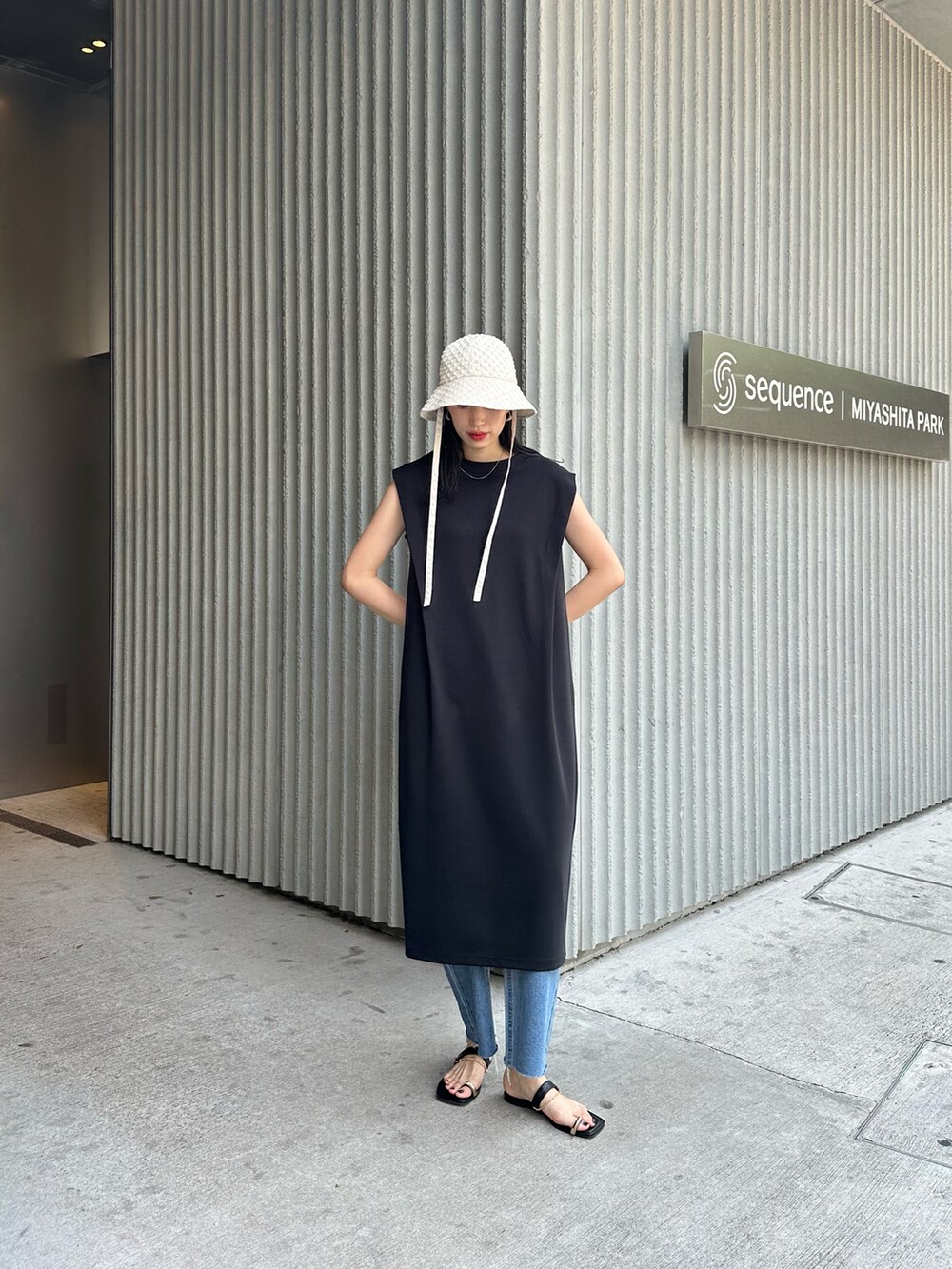 ブラック系のワンピース、ブルー系のデニムパンツ、ブラック系のサンダルを着用したレディースの春コーディネートの2枚目の写真
