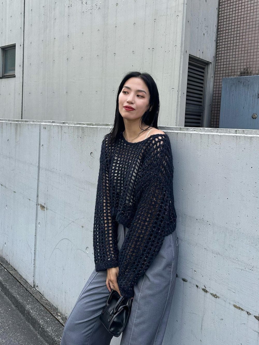 ブルー系のニット/セーター、ブラック系のショルダーバッグを着用したレディースの夏コーディネートの3枚目の写真