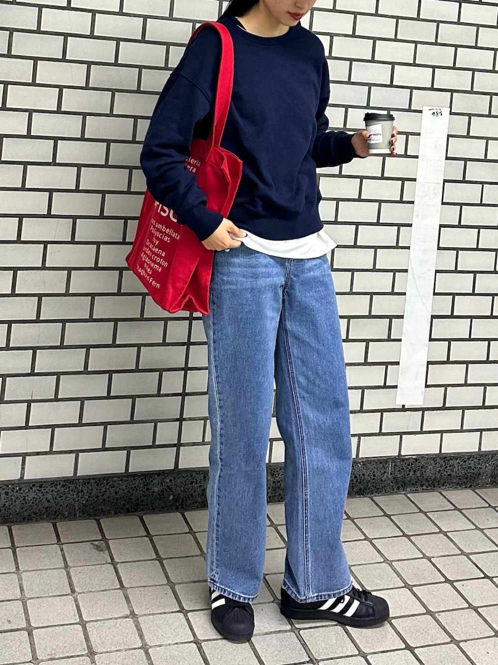 ブルー系のスウェット、レッド系のトートバッグ、ホワイト系のTシャツ/カットソーを着用したレディースの春コーディネートの2枚目の写真