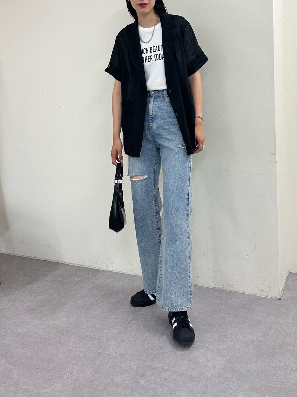 ブルー系のデニムパンツ、ホワイト系のTシャツ/カットソー、ブラック系のジャケット/アウターを着用したレディースの春コーディネートの2枚目の写真