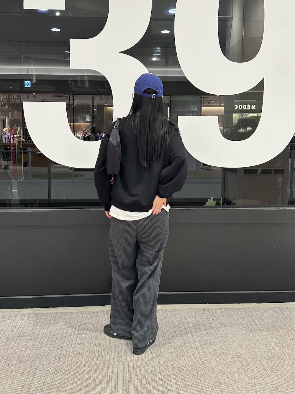 ブラック系のスウェット、ホワイト系のTシャツ/カットソー、グレー系のスラックスを着用したレディースの秋コーディネートの3枚目の写真