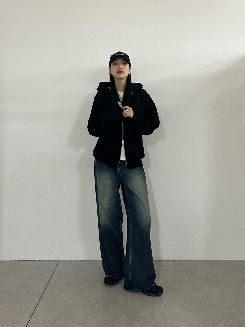 ブラック系のパーカー、ブルー系のデニムパンツ、ブラック系のキャップを着用したレディースの秋コーディネートの4枚目の写真