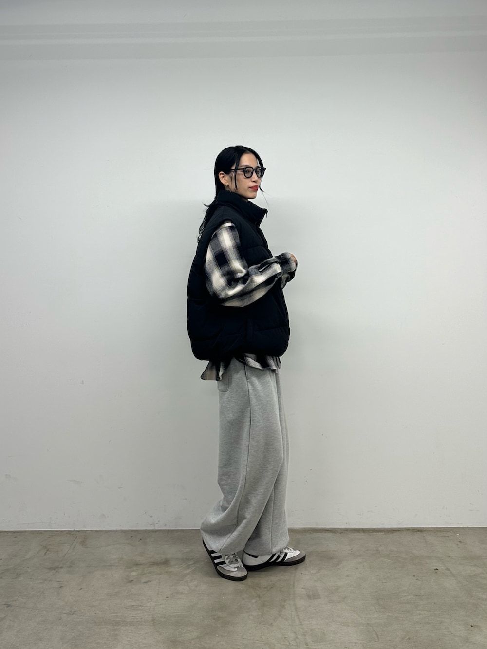 グレー系のスウェットパンツ、ブラック系のダウンベスト、ブラック系のトップスを着用したレディースの秋コーディネートの2枚目の写真