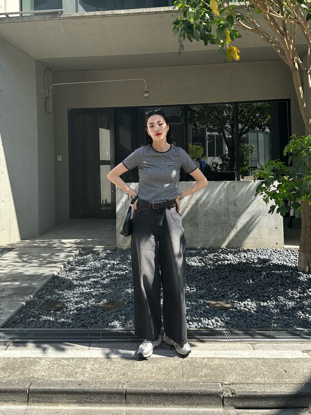 ブラック系のデニムパンツ、ブラック系のTシャツ/カットソー、ブラック系のショルダーバッグを着用したレディースの春コーディネートの2枚目の写真