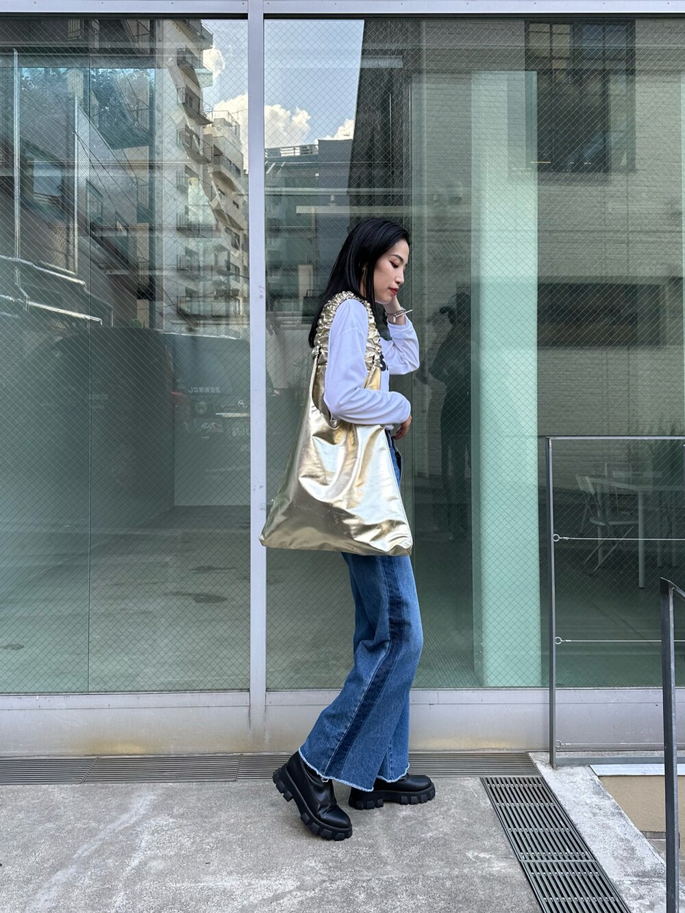 ブルー系のデニムパンツ、ブラック系のブーツ、ホワイト系のTシャツ/カットソーを着用したレディースの夏コーディネートの2枚目の写真